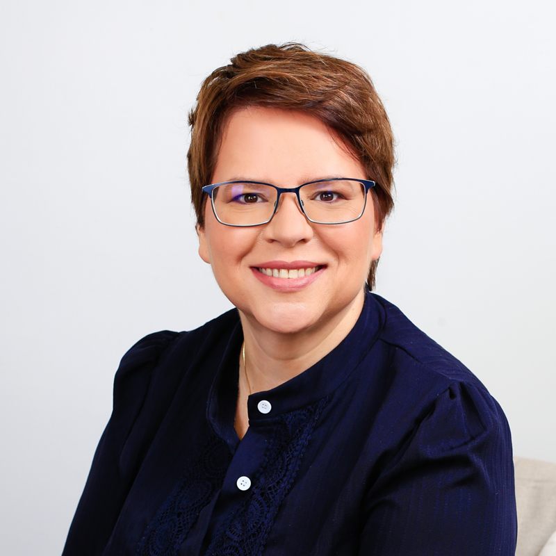 Retrato de Micheline Paschke, psicóloga clínica em Passo Fundo, sorrindo, de blusa azul-marinho